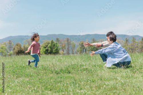 草原・公園で両親に走って抱きつく活発な子供（女の子） 