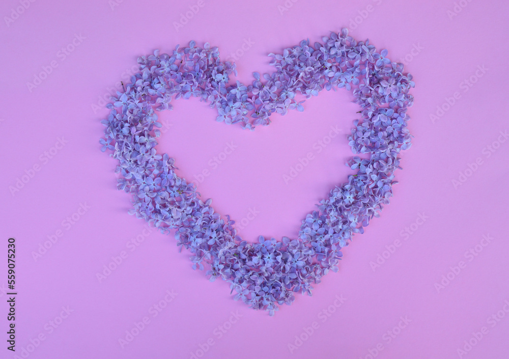 Lilac flowers in heart shape on the pink background. Flat lay.