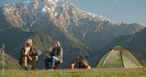 Senior tourist couple travellers hiking in nature, sitting and talking at the top of the mountains. photo