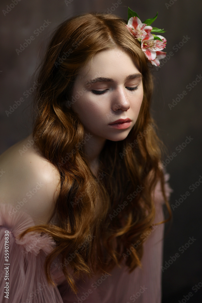 Young woman with long red curly hair in pink fairy dress with open shoulders and puff sleeves with pink flower in hair. Romantic portrait of girl on brown background