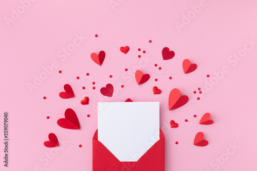 Saint Valentine day holiday background with envelope, paper card and various red hearts for love romantic message. Flat lay composition..