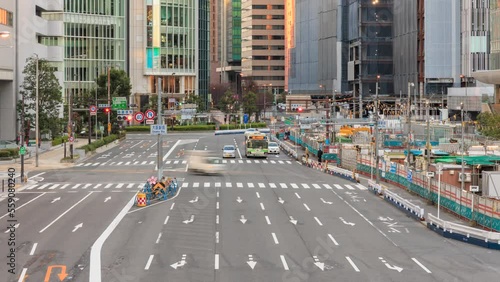 Light traffic and pedestrians on wide road between office buildings and Japan Railways station