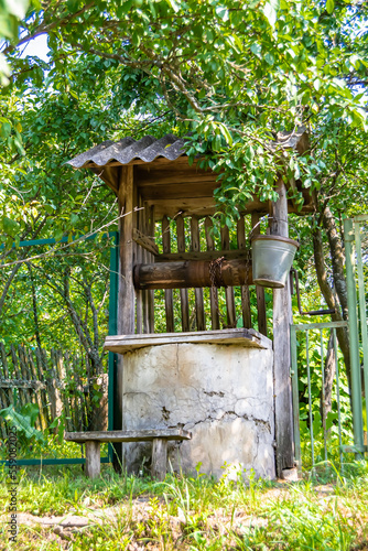 Old well with iron bucket on long forged chain for clean drinking water