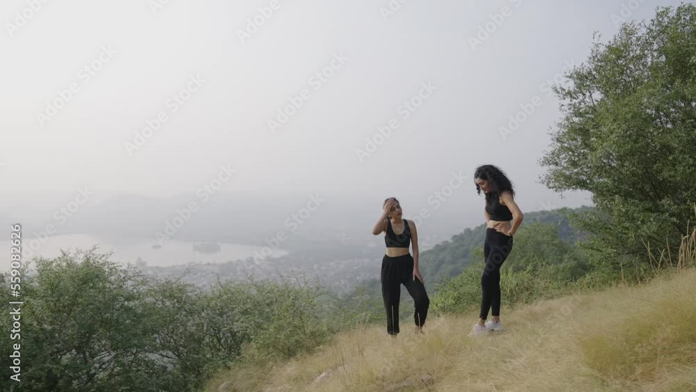 young Indian two women smiling climbs at the morning.Asian young girl standing climb hiking raced and breathing relax.Hikers celebrating at mountain top Two female hikers celebrating on the mountain. young Indian two women smiling climbs at the morning.Asian young girl standing climb hiking raced and breathing relax.Hikers celebrating at mountain top Two female hikers celebrating on the mountain.