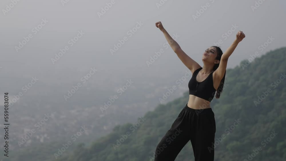 Close-up young beautiful girl climb on the top of mountain. Indian young female breath and fitness runner on top happy and celebrating success.Female runner on top of the world cheering in winning. Close-up young beautiful girl climb on the top of mountain. Indian young female breath and fitness runner on top happy and celebrating success.Female runner on top of the world cheering in winning.