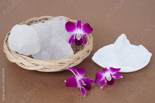 Crystal clear alum stones or Potassium alum on basket, decorated with flowers. Useful for beauty and spa treatment. Use to treat body odor under the armpits as deodorant and make water clear.          photo