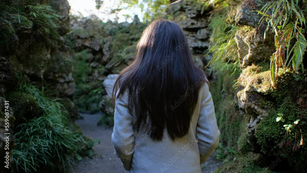 Young Woman Shot From Back Walking Through Natural Stone Walls Young Woman Shot From Back Walking Through Natural Stone Walls