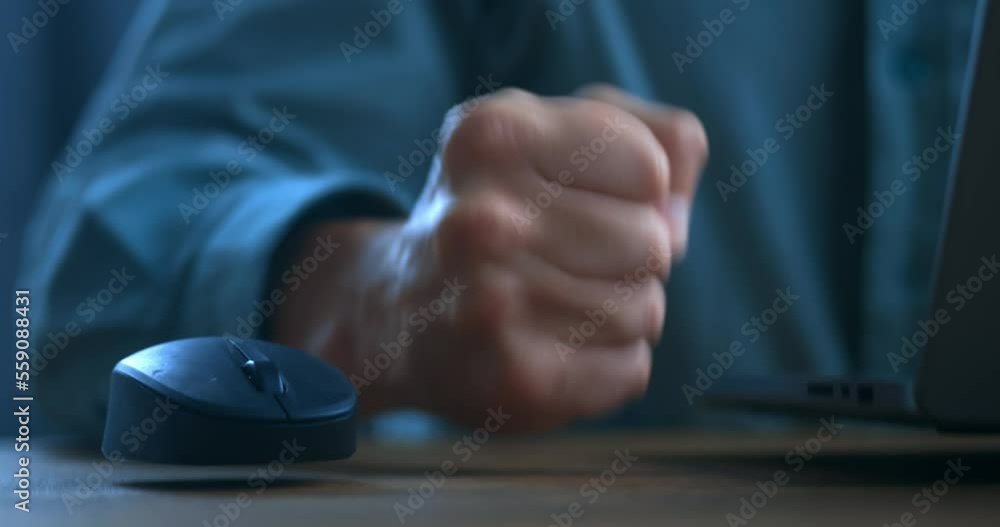 Angry business man is dissatisfied with the work at the computer mouse and hits the table with his fist. The concept of showing anger while working at a laptop, close-up. Problems with online business Angry business man is dissatisfied with the work at the computer mouse and hits the table with his fist. The concept of showing anger while working at a laptop, close-up. Problems with online business