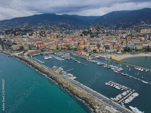 Aerial view of Sanremo, Italian city on the seashore in Liguria, north Italy. Drone flying along the port over beaches and boardwalk with palm trees and Birds Eye of yacht parking in San Remo, Italy.