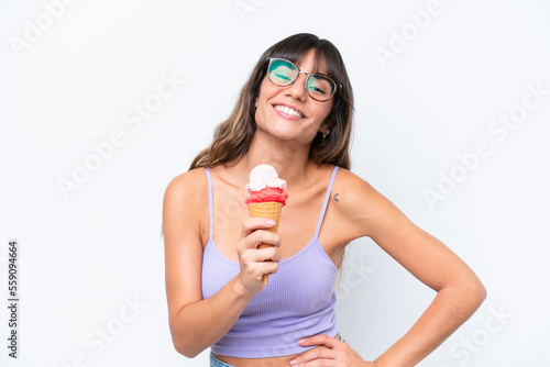 Young caucasian woman with a cornet ice cream over isolated white background posing with arms at hip and smiling