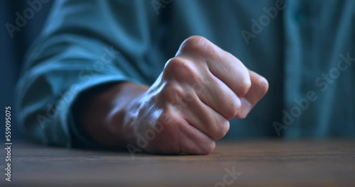 Close up man lose temper, aggressive male clenches his hand into a fist and angrily hits the table. Male flash of rage. Losing temper and and display of aggression concept.