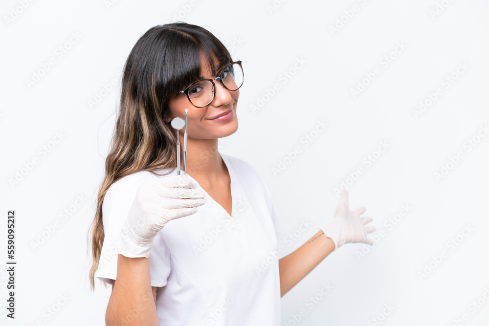Dentist caucasian woman holding tools isolated on white background extending hands to the side for inviting to come Dentist caucasian woman holding tools isolated on white background extending hands to the side for inviting to come