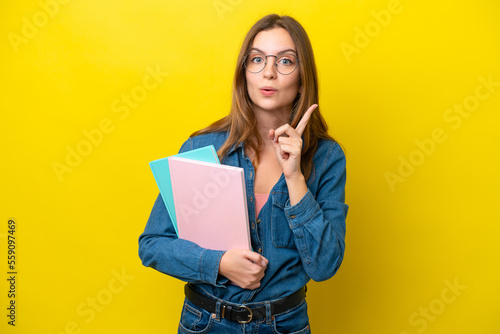 Young student caucasian woman isolated on yellow background intending to realizes the solution while lifting a finger up