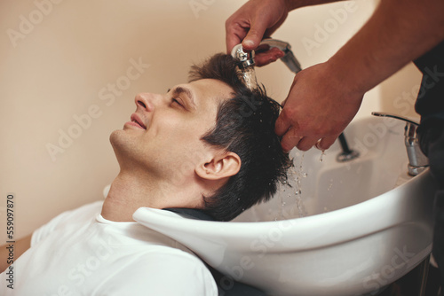 Barber washing hair of caucasian man , close-up