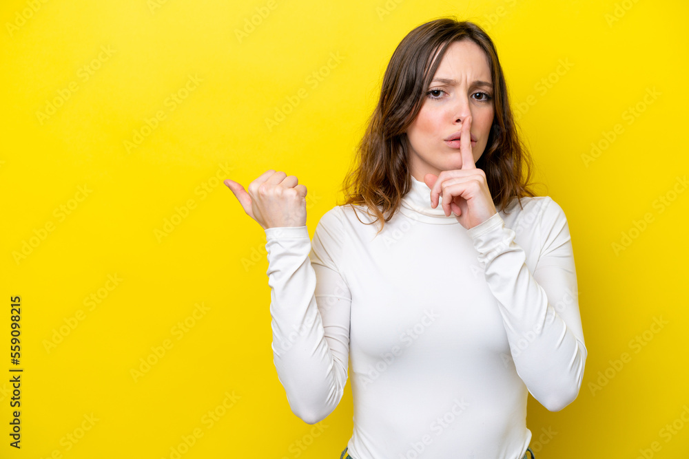 Young caucasian woman isolated on yellow background pointing to the side and doing silence gesture Young caucasian woman isolated on yellow background pointing to the side and doing silence gesture
