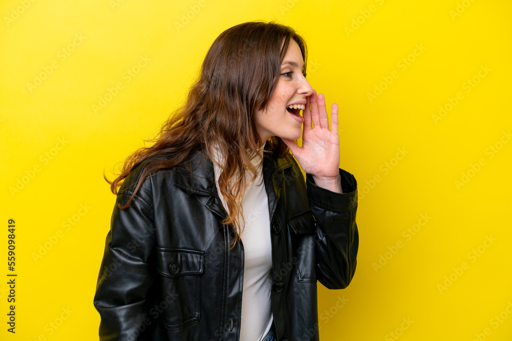 Young caucasian woman isolated on yellow background shouting with mouth wide open to the side Young caucasian woman isolated on yellow background shouting with mouth wide open to the side