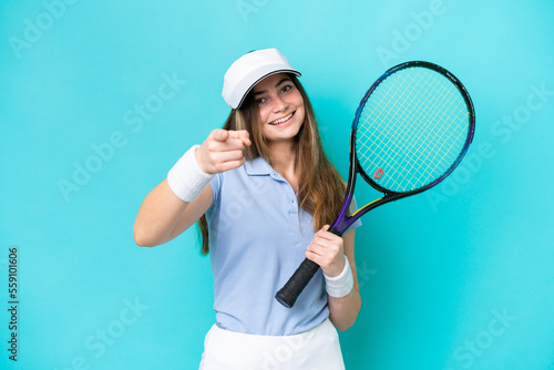 Young tennis player woman isolated on blue background pointing front with happy expression © luismolinero