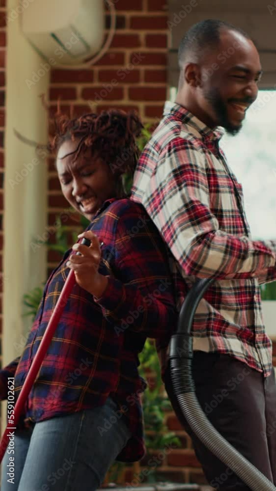 Vertical video Happy partners showing silly dance moves and cleaning