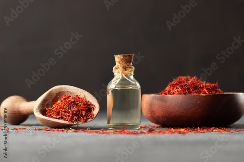 Foto Glass bottle of saffron essential oil with dried saffron, spice or herb oil conc
