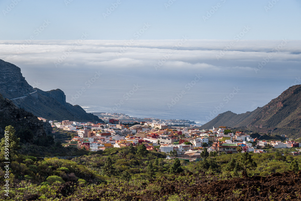 View of a Town, Ocean and Thick Clouds from Uphill, Surrounded by Tall Mountains