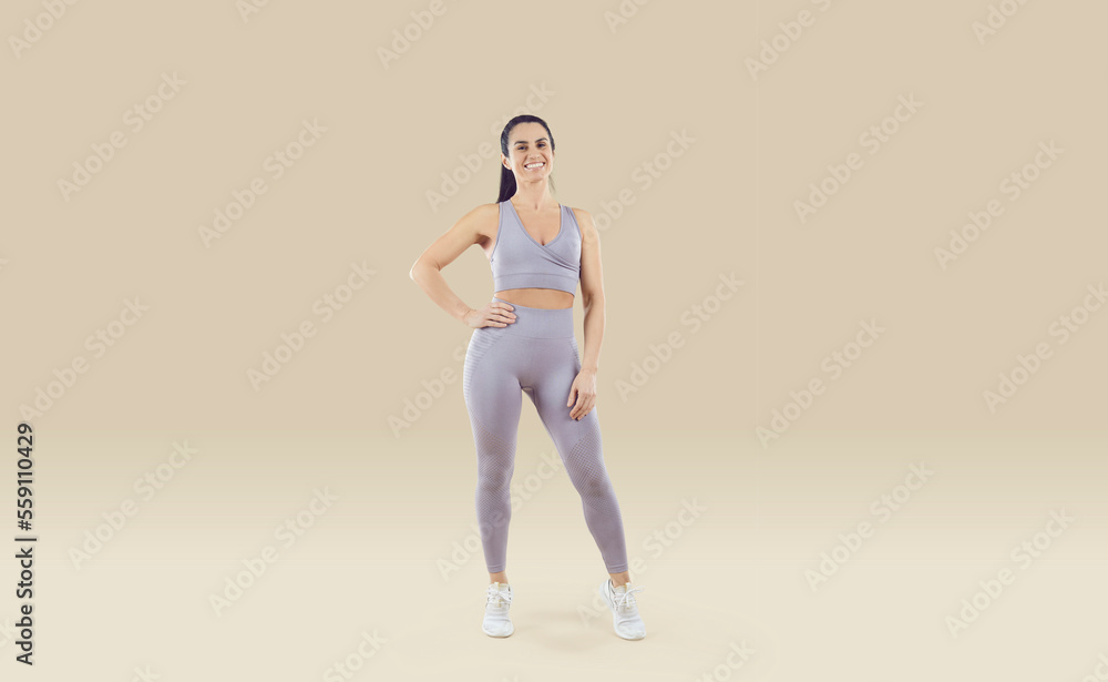 Fit and healthy woman. Portrait of happy sportswoman dressed in comfortable sportswear set isolated on beige background. Full length of smiling young woman with athletic body in light lilac sportswear Fit and healthy woman. Portrait of happy sportswoman dressed in comfortable sportswear set isolated on beige background. Full length of smiling young woman with athletic body in light lilac sportswear