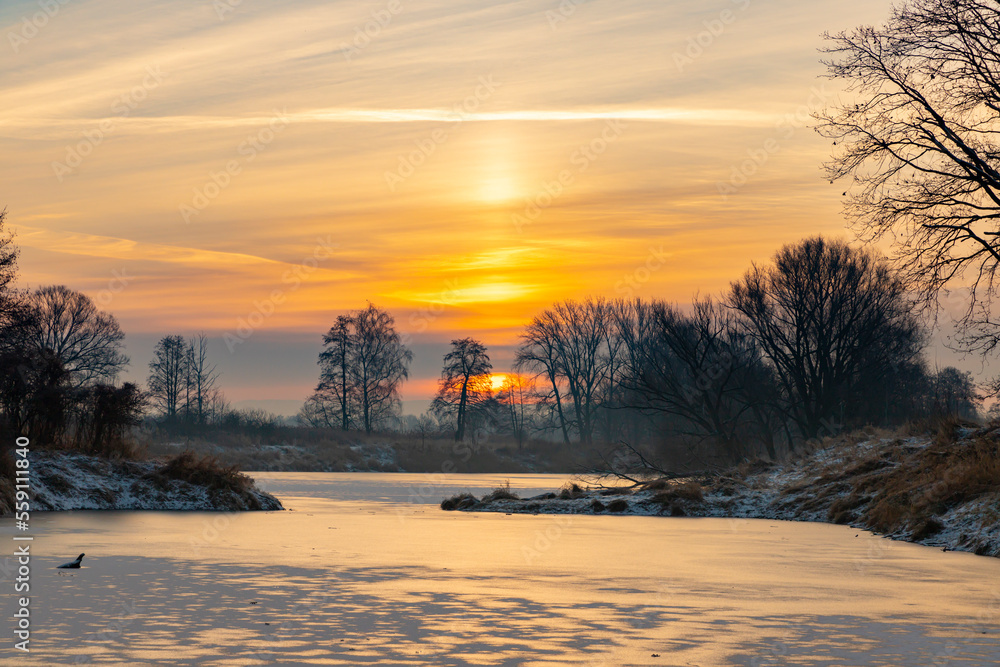 Krajobraz zimowy. Widok ze wschodem słońca i zimowy poranek nad rzeką. Zamrożona rzeka. Świtanie w zimowej scenerii. Mroźny poranek. Tło natury. Krajobraz zimowy. Widok ze wschodem słońca i zimowy poranek nad rzeką. Zamrożona rzeka. Świtanie w zimowej scenerii. Mroźny poranek. Tło natury.