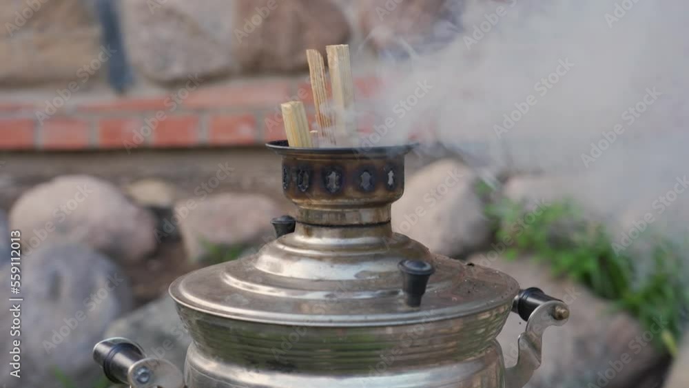 Old russian wood-burning samovar with smoke. Tea party on terrace of country house Old russian wood-burning samovar with smoke. Tea party on terrace of country house
