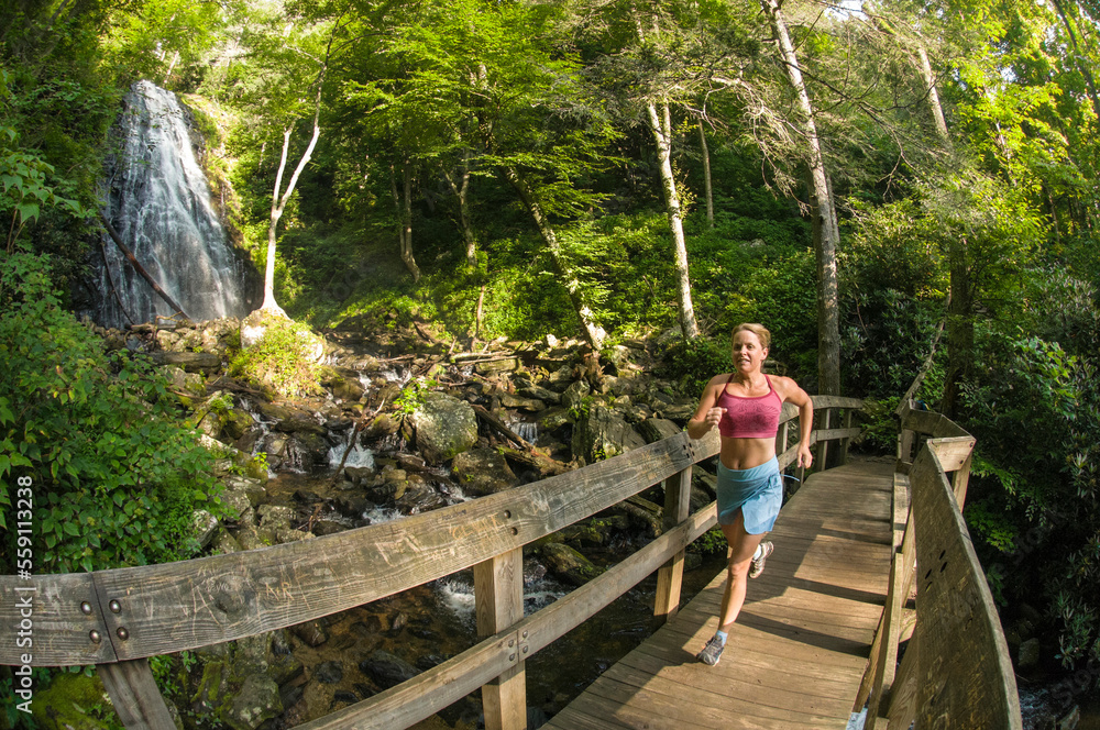 A woman trail running neaer waterfall, Pisgah National Forest, Burnsville, North Carolina. A woman trail running neaer waterfall, Pisgah National Forest, Burnsville, North Carolina.
