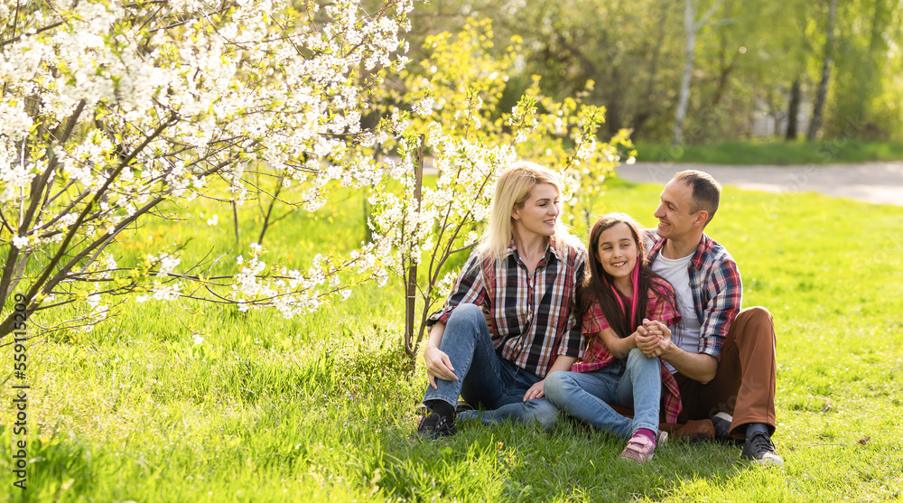 Outdoor portrait of happy young family playing in spring park under blooming tree, lovely couple with little child having fun in sunny garden Outdoor portrait of happy young family playing in spring park under blooming tree, lovely couple with little child having fun in sunny garden