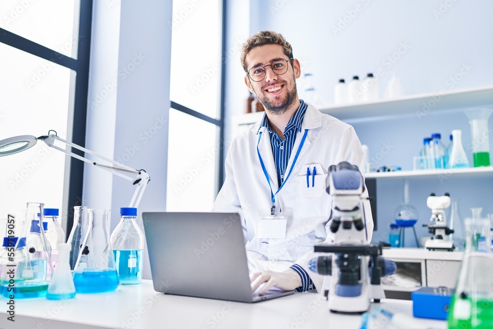 Young man scientist smiling confident using laptop at laboratory Young man scientist smiling confident using laptop at laboratory