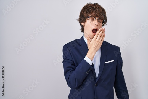 Hispanic business young man wearing glasses bored yawning tired covering mouth with hand. restless and sleepiness.