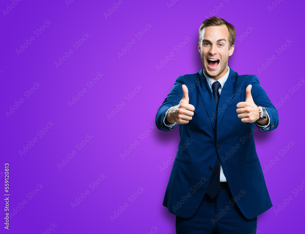 Happy excited businessman showing two thumbs up like hand gesture, in blue confident suit, over violet purple colour background. Very cheerful man. Copy space for ad, slogan or text. Happy excited businessman showing two thumbs up like hand gesture, in blue confident suit, over violet purple colour background. Very cheerful man. Copy space for ad, slogan or text.