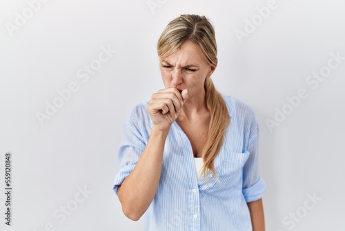 Beautiful blonde woman standing over white background feeling unwell and coughing as symptom for cold or bronchitis. health care concept.