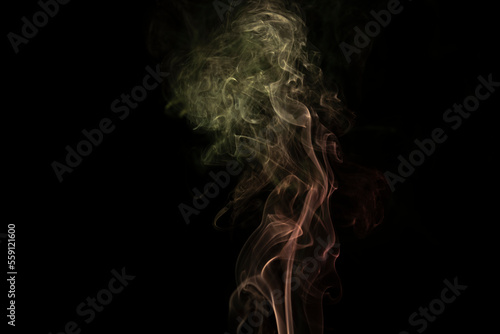incense stick with yellow green smoke against black background
