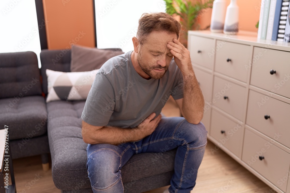 Middle age man suffering for head and stomach ache at home Middle age man suffering for head and stomach ache at home