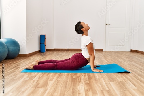 Young hispanic woman smiling confident training yoga at sport center