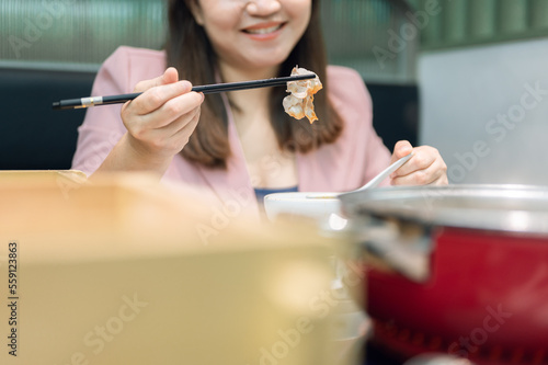 Asian woman using chopsticks to put food into her mouth