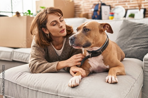 Young caucasian woman smiling confident lying on sofa with dog at new home