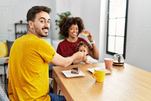 Couple and daughter having breakfast sitting on table at home