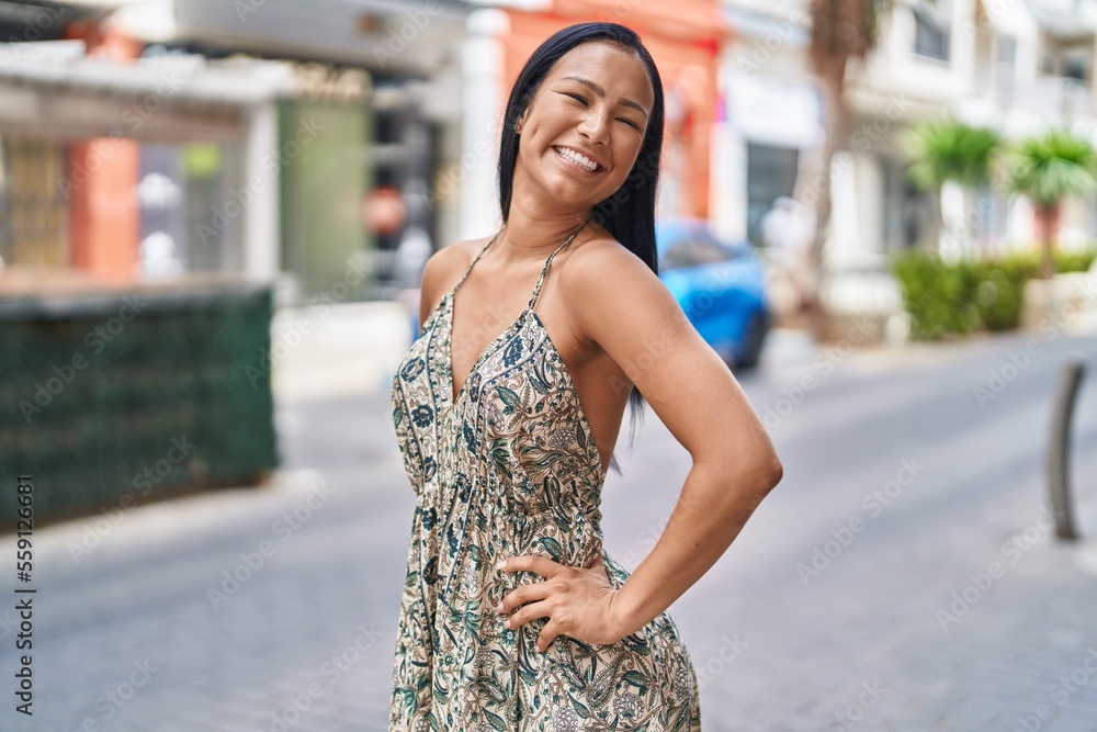 Fototapeta premium Young beautiful latin woman smiling confident looking to the side at street