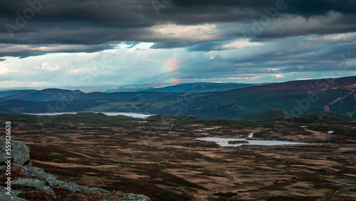 Mountain landscape with rainbow in Jotunheimen National Park with lakes and cloudy sky in Norway