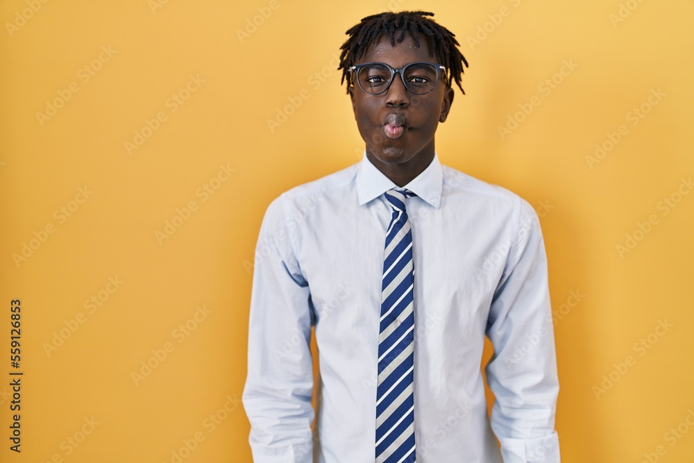 African man with dreadlocks standing over yellow background making fish face with lips, crazy and comical gesture. funny expression. African man with dreadlocks standing over yellow background making fish face with lips, crazy and comical gesture. funny expression.