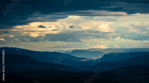 Mountain silhouette layers in the landscape of Jotunheimen National Park in Norway  dark and colorful clouds in the sky