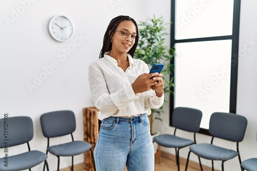 Young african american woman smiling confident using smartphone at waiting room