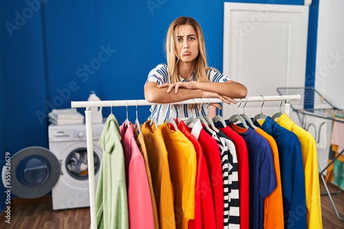 Young blonde woman at laundry room with clean clothes depressed and worry for distress, crying angry and afraid. sad expression.