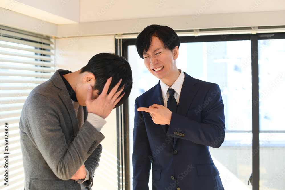 男性社員を怒る男性のビジネスマン 男性社員を怒る男性のビジネスマン