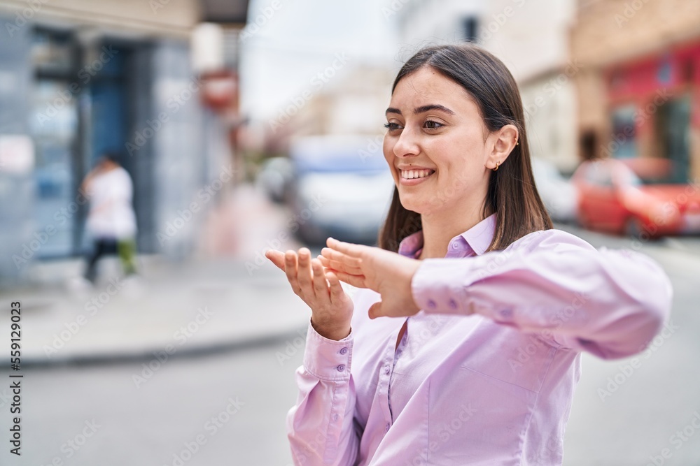 Young hispanic woman smiling confident doing spend money gesture at street