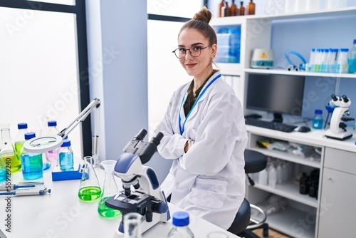 Young woman scientist sitting with arms crossed gesture at laboratory