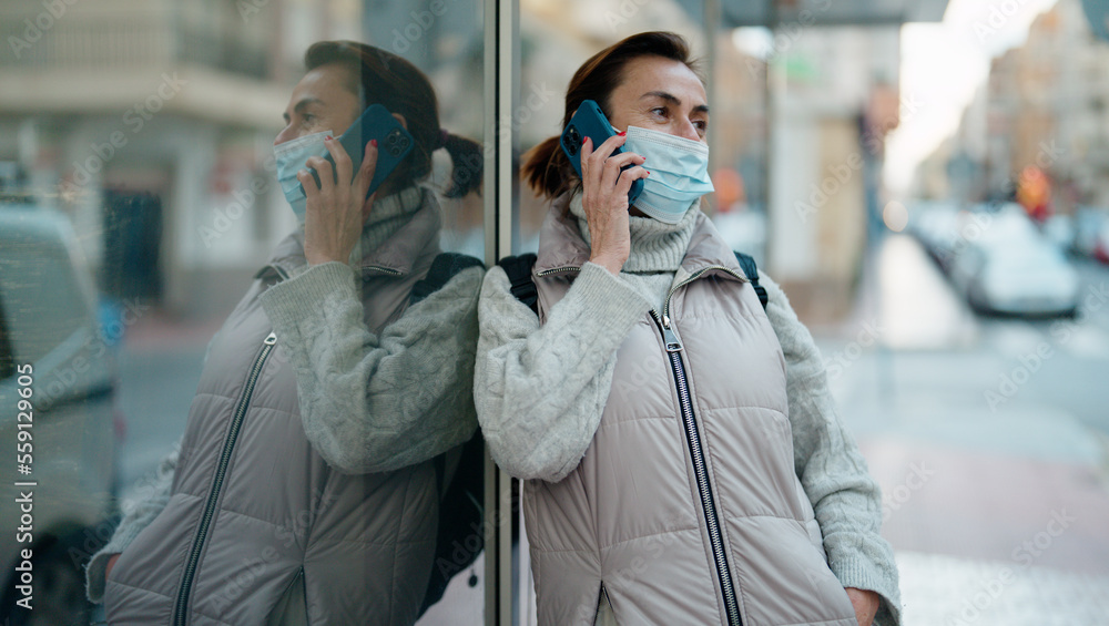 Middle age hispanic woman wearing medical mask talking on the smartphone at street Middle age hispanic woman wearing medical mask talking on the smartphone at street
