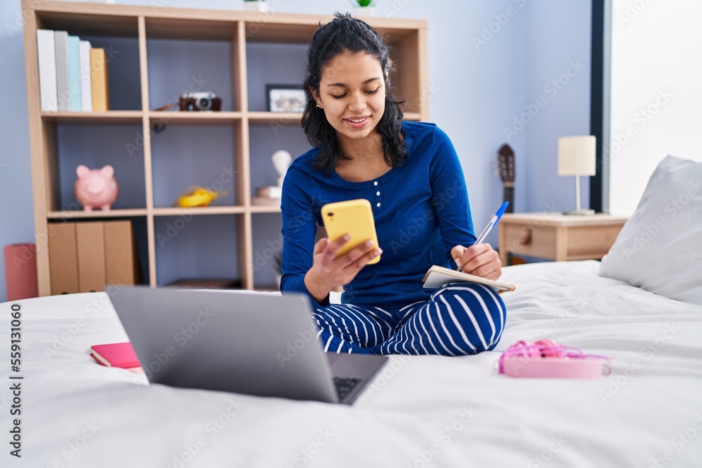 Young latin woman sitting on bed studying at bedroom Young latin woman sitting on bed studying at bedroom